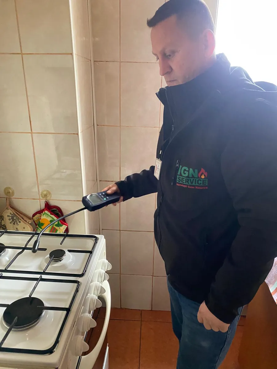 Tehnician IGN Service verifică etanșeitatea unui aragaz cu detector de scăpări de gaz în bucătărie