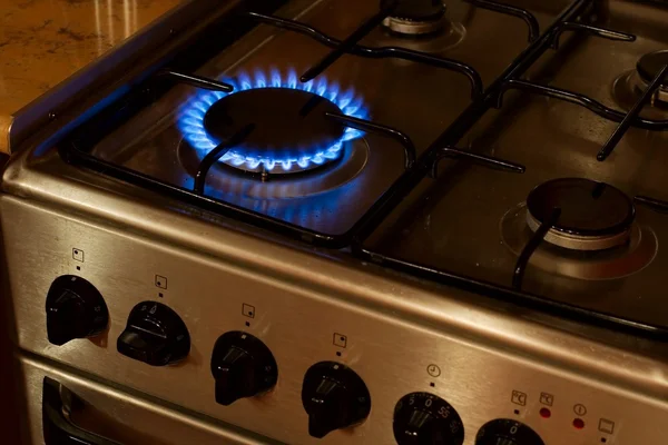 Aragaz din inox cu un arzator aprins cu flacara albastra de gaz in bucatarie