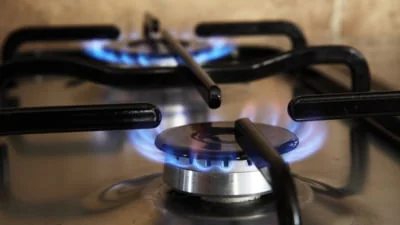 Arzătoare aprinse cu flacără albastră pe o plită pe gaz, văzute de aproape printre grătare
