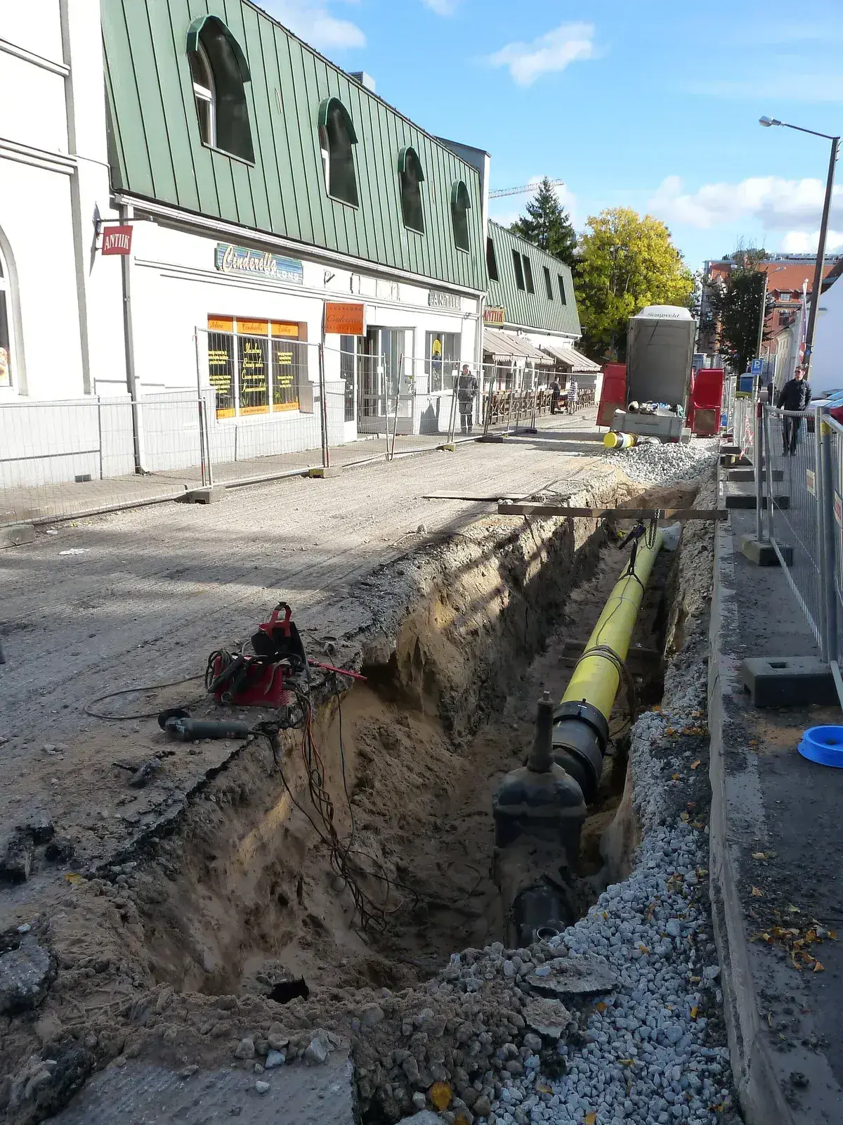 Șanț adânc pe o stradă, cu conductă galbenă de gaze naturale și robinet de secționare montat