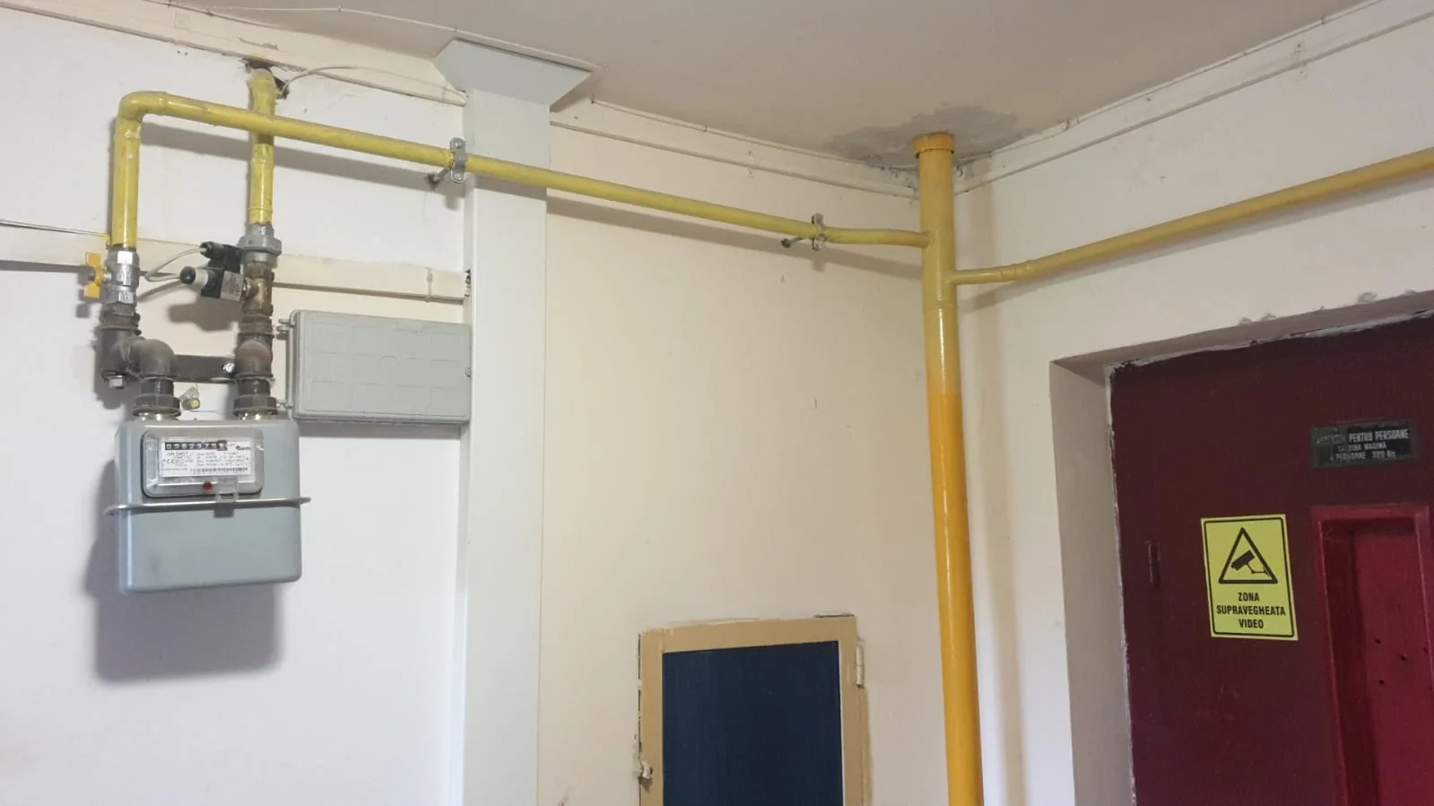 Conducte de gaz galbene și contor montate pe holul unui bloc de locuințe
