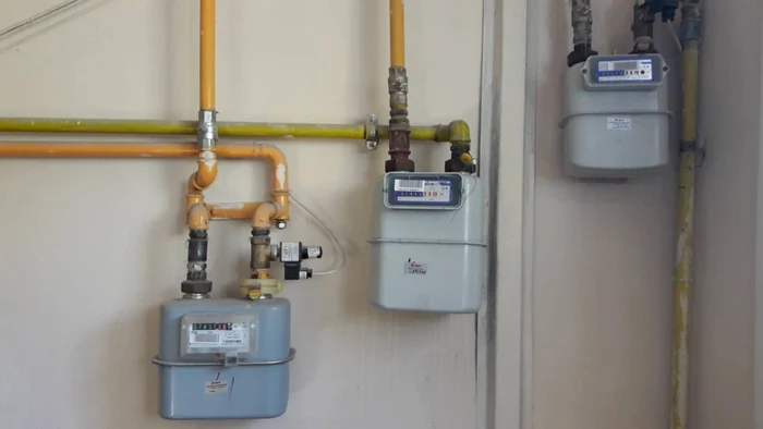 Mai multe contoare de gaz și conducte galbene montate pe peretele unei clădiri
