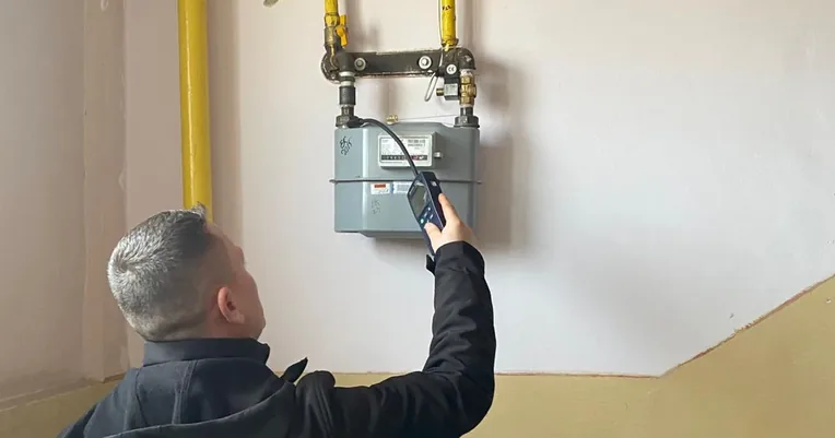 Tehnician IGN Service verifică contoarele de gaz de pe casa scării cu detectorul electronic
