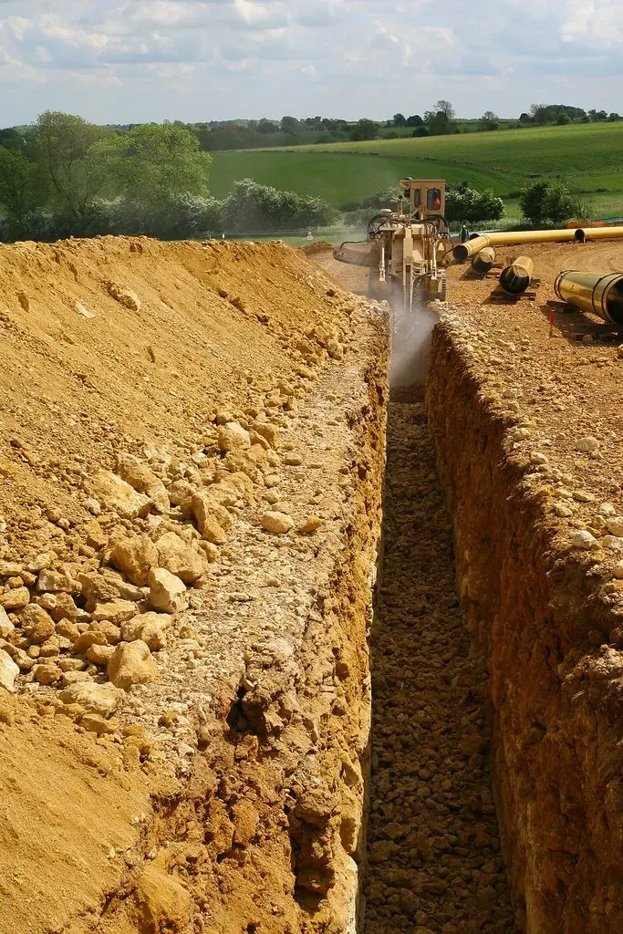 Lucrare branșament gaz: șanț săpat cu conductă galbenă și utilaj de excavare