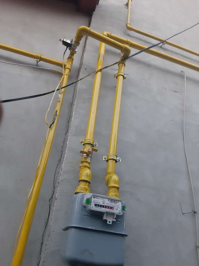 Instalație gaz pe perete exterior: contor și țeavă galbenă montate pe clădire nouă