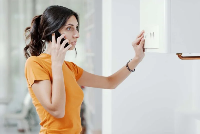 Femeie suna la telefon cerand ajutor langa centrala termica de perete