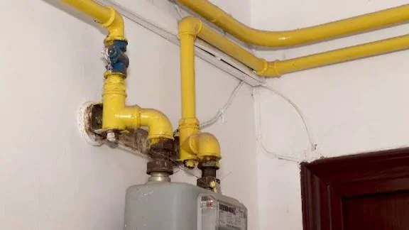 Instalatie de gaz cu tevi galbene, robinet albastru si contor de gaz montate pe perete