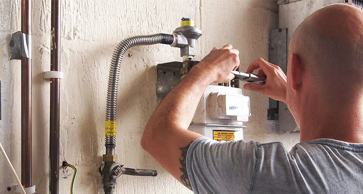 Tehnician IGN Service cu geanta de scule pe umăr merge pe stradă, pe lângă conductele galbene de gaz de pe fațadă