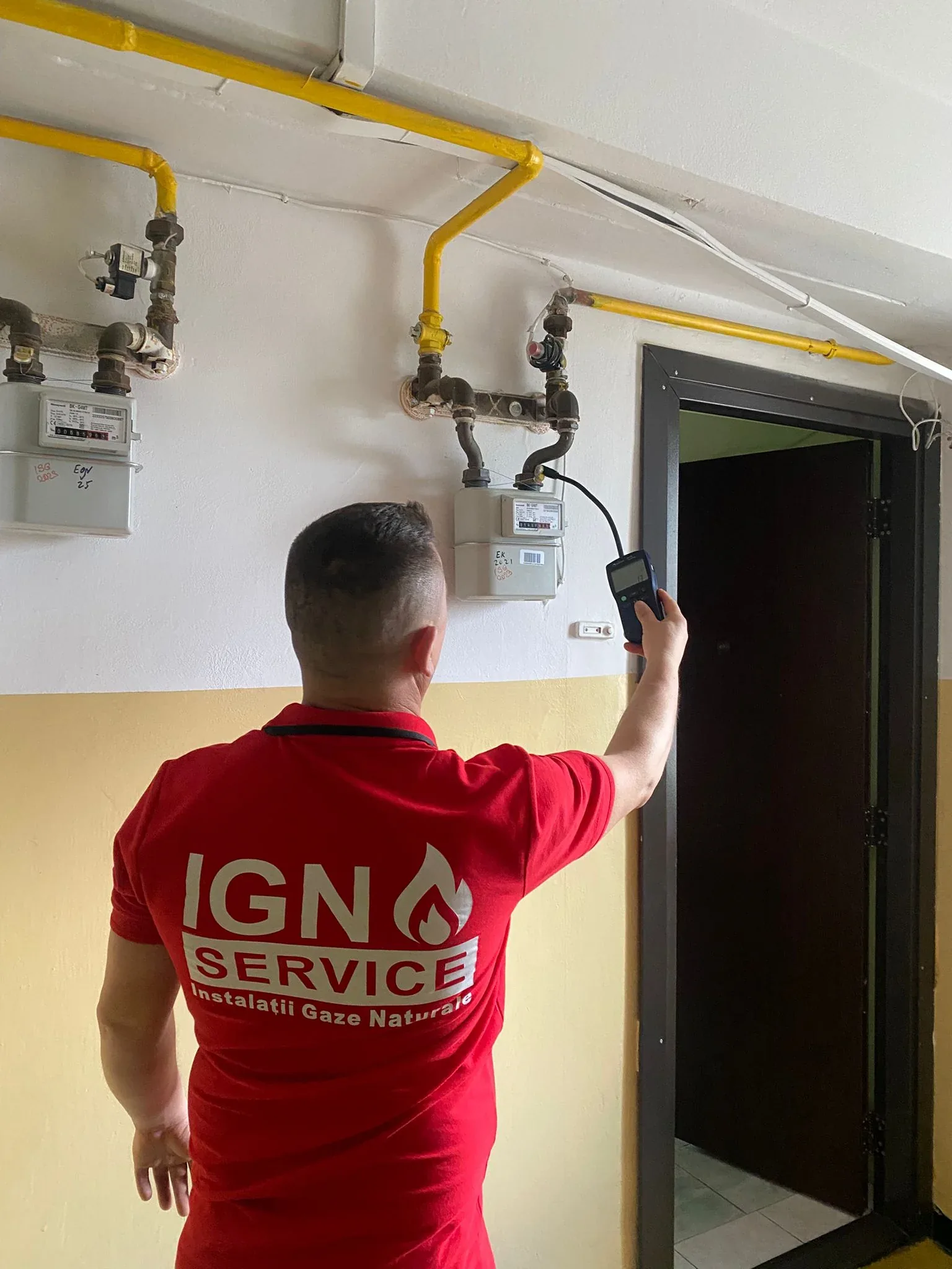 Instalator IGN Service verifică cu detector electronic contorul de gaz din casa scării unui bloc din Iași