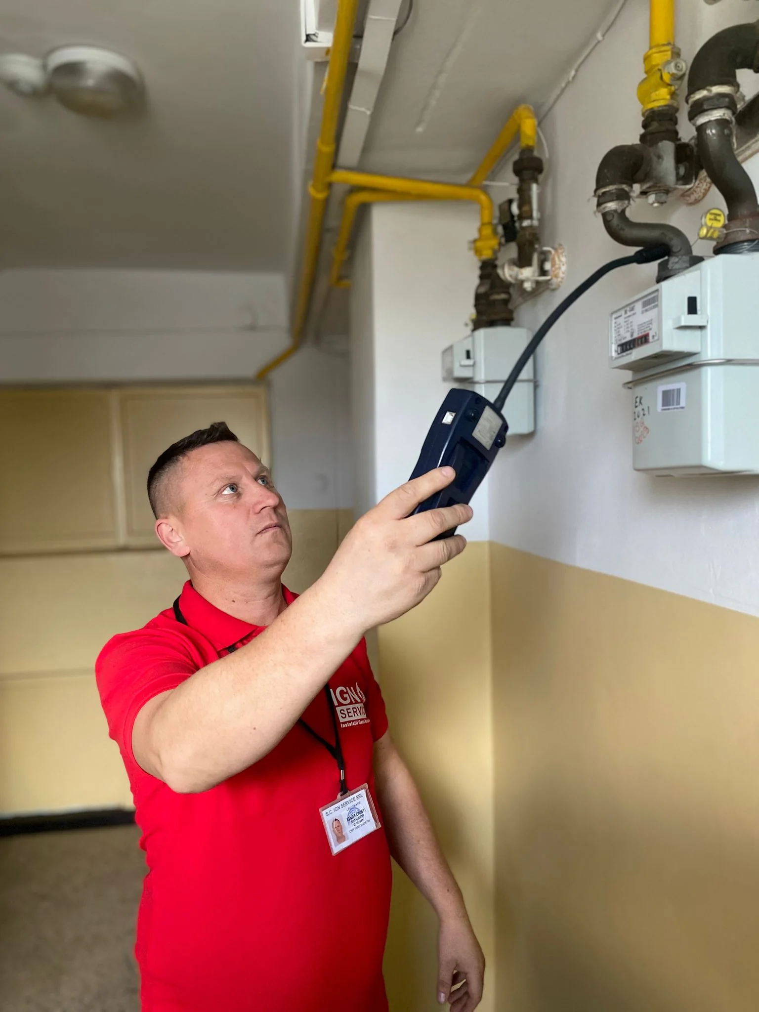 Tehnician IGN Service verifică cu detectorul electronic contoarele de gaz de pe casa scării