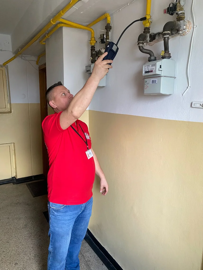 Tehnician IGN Service verifică cu detector portabil contorul de gaz și țevile din casa scării