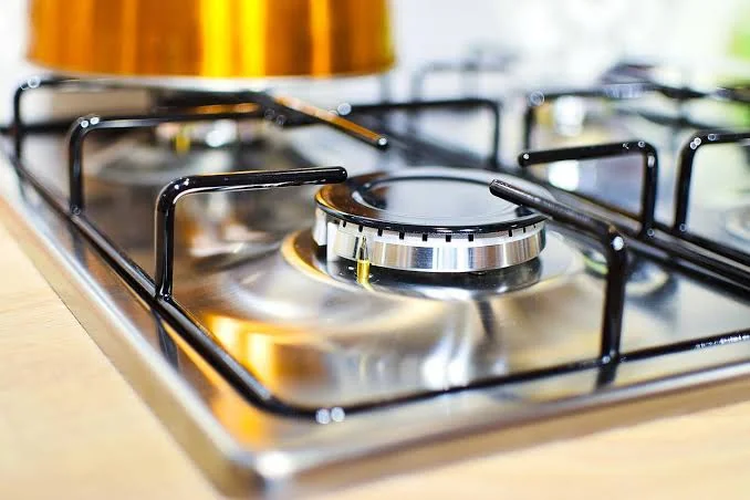 Plită pe gaz din inox cu arzător central și un vas de gătit deasupra, prim-plan
