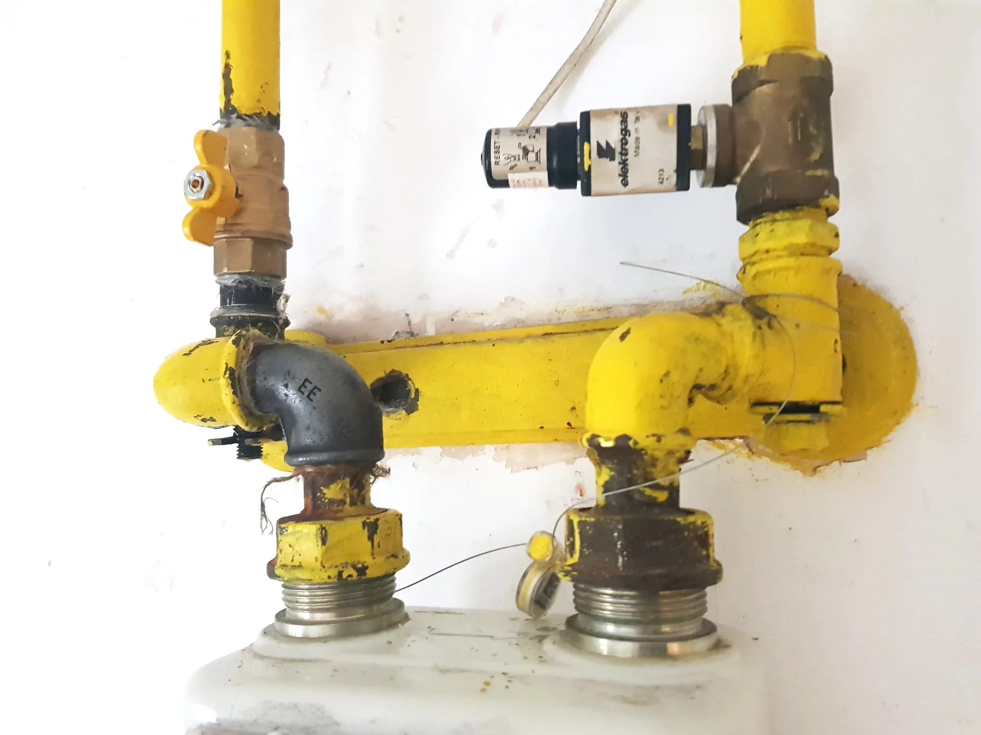 Robinet, electrovalvă și fitinguri galbene la racordul contorului de gaz, cu fir de sigiliu