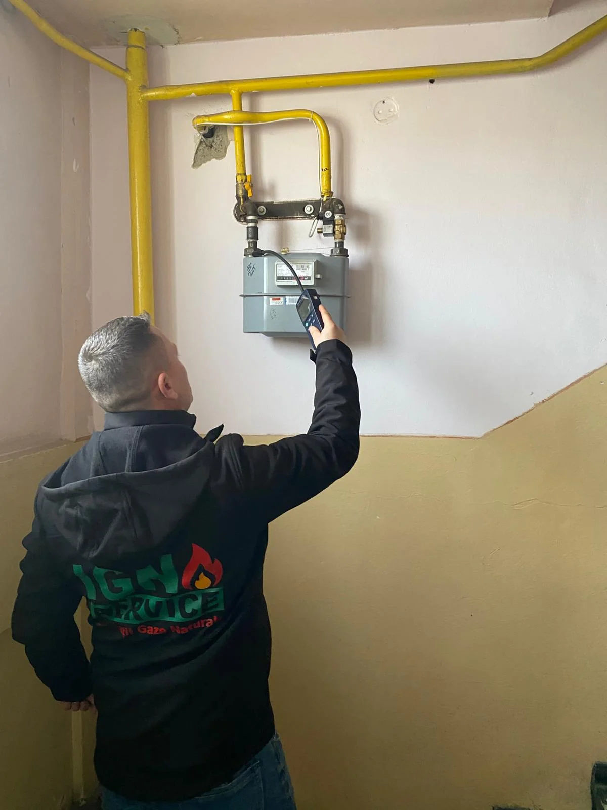 Tehnician IGN Service măsoară cu un detector electronic scăpările la contorul de gaz al unui bloc