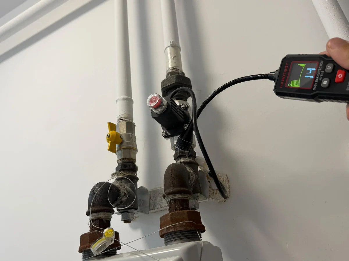 Detector de gaz apropiat de electrovalva neagră și robinetul galben de pe țevile de deasupra contorului