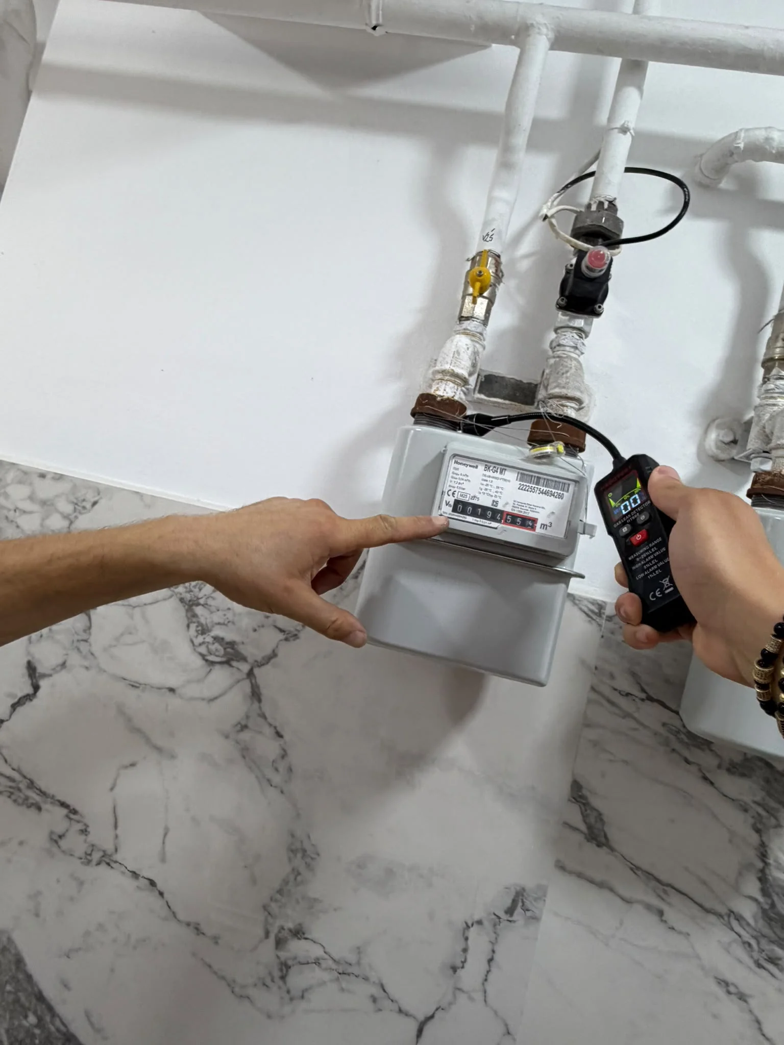 Instalator în geacă IGN Service verifică cu detectorul electronic un contor de gaz pe casa scării, Botoșani