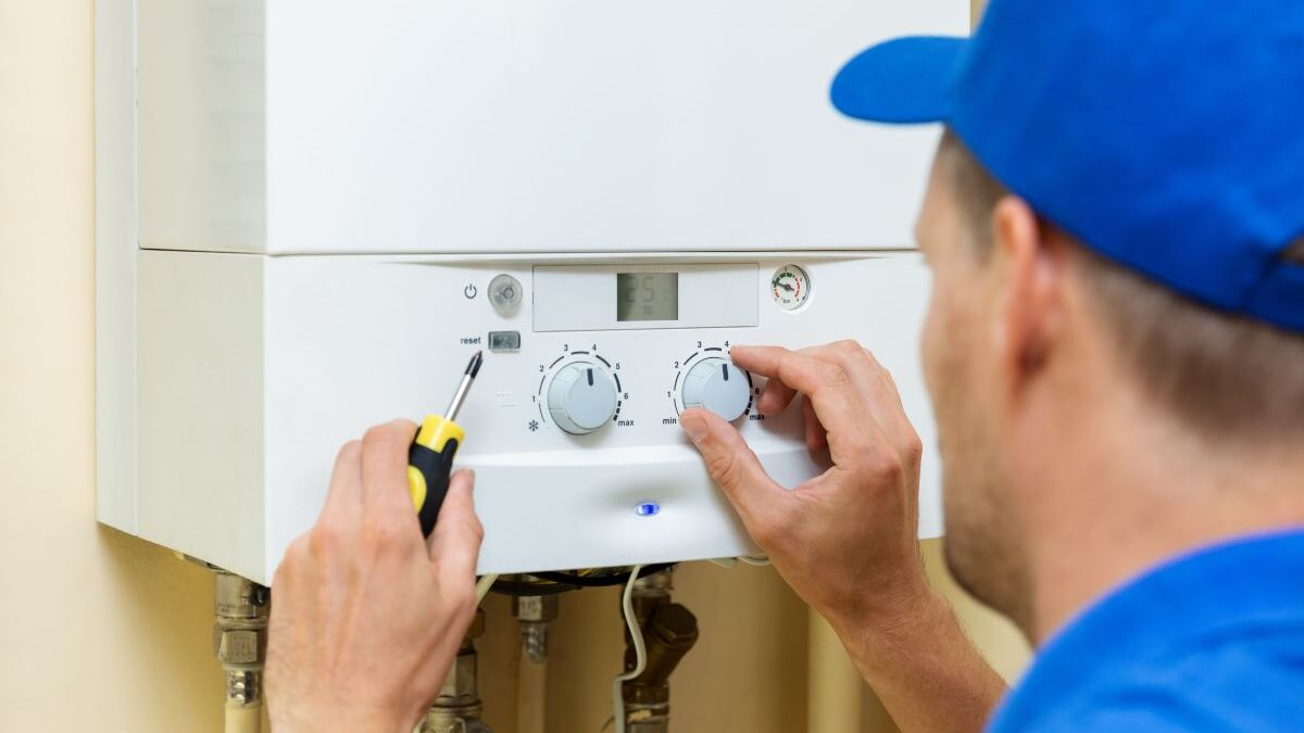 Tehnician reglează butoanele unei centrale termice pe gaz de perete